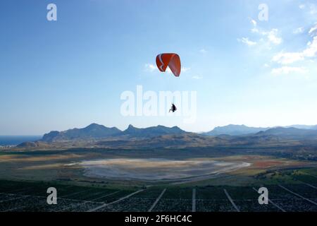 Landscape view of a paraglider flying over beautiful mountains and a sky with sun rays, Mount Klementieva, Russia Stock Photo