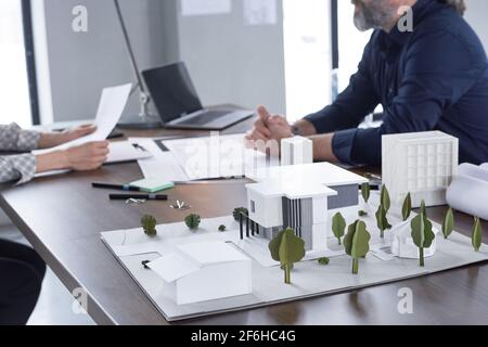 Image of little architectural model on the table with architects working in the background Stock Photo