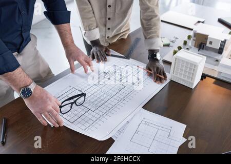 Close-up of two architects drawing blueprint on new project together at the table and discussing it Stock Photo