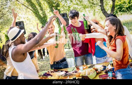 Young multiracial friends toasting beer at barbecue garden party - Friendship concept with happy people having fun at backyard summer camp Stock Photo