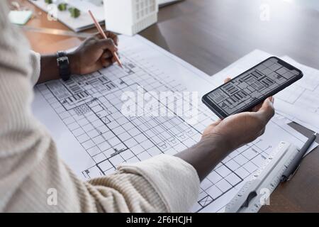 Close-up of architect using the photo on his mobile phone and drawing the copy on the paper at the table Stock Photo