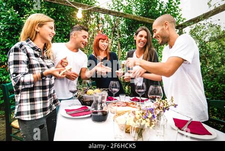 Young people having fun eating local food and drinking red wine at country side garden fest - Friendship and life style concept with happy friends Stock Photo