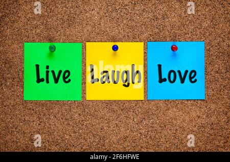 Three colored notes on corkboard with words Live, Laugh, Love. Close-up Stock Photo