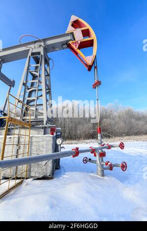 Oil pumpjack winter work. Oil pressure gauge shows 10 ATM (Max 15 Bar - red line).  A pumpjack is the overground drive for a reciprocating piston pump Stock Photo