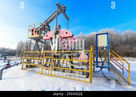 Oil pumpjack winter work is the overground drive for a reciprocating piston pump in an oil well. It is used to mechanically lift liquid out of the wel Stock Photo