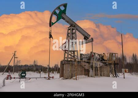 Russia Green Oil pump oil rig energy industrial machine for petroleum crude. oil crisis. Pumps oil pollution. Fiery red clouds from the glow of the su Stock Photo