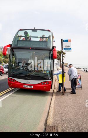 Senior couple boarding a bus in Southend on Sea, Essex, UK. Ensignbus open top Seaside Special bus route. Bus stop on seafront Stock Photo