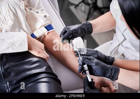 Process of taking blood sample in blood tube from a patient in a chair in beauty salon. Stock Photo