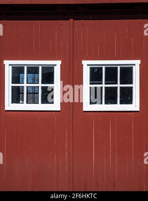 Photo of a side of a red barn with two white framed windows. Stock Photo