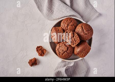 Homemade chocolate cupcakes in bowl with napkin on wooden light background, top view, copy space Stock Photo
