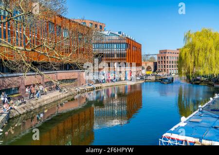 LONDON, UK - MARCH 29 2021: People enjoy sunshine on the bank of Regent's Canal in Camden Town in London. Stock Photo