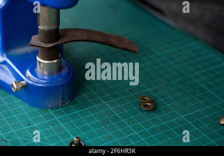 Artisan using hand press for setting snaps in leather for makes a wallet. Hand Pressure Snap Pressing Machine is using by craftsman in leather Stock Photo