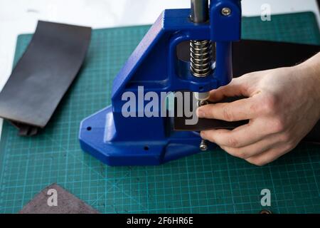 Artisan using hand press for setting snaps in leather for makes a wallet. Hand Pressure Snap Pressing Machine is using by craftsman in leather Stock Photo
