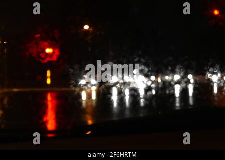 cars stopped at traffic lights with raindrops on the glass and reflections on the flooded road. Taken during floods in Sydney during March 2021. Stock Photo