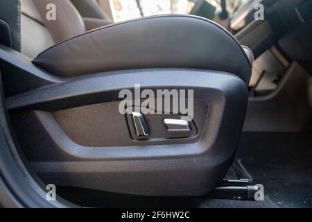 car seat electronic switch button. lever for electronic seat adjustment in a modern premium car. seat memory option. close upof seat bottoms Stock Photo
