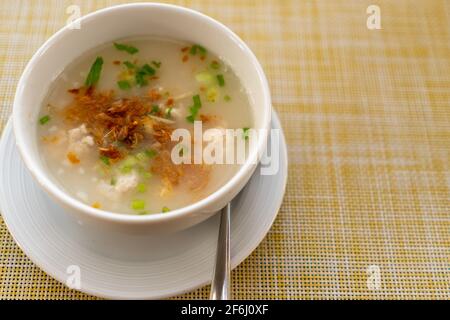 Thai style breakfast pork rice soup with egg on wood table. Copy space put your text on background. Stock Photo