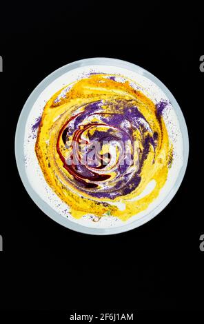 A plate with yellow paint and circular stains on a dark background.Abstract art. Search for material for art work. Stock Photo