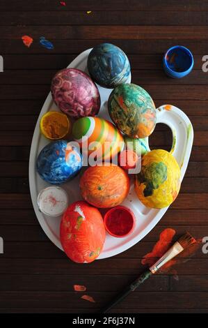 A palette with home-painted Easter eggs on old wooden background. Stock Photo