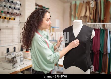 Femail Tailor, seamstress, fashion designer working with clothes on dummy in workshop studio Stock Photo