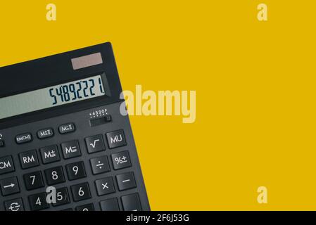 Calculator isolated on yellow background with copy space. Black calculator with numbers on the screen. Top view, flat lay. Stock Photo