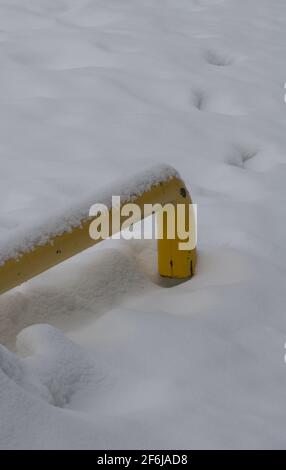 yellow pipe in deep snow with fresh snow on top vertical winter backdrop background or wallpaper with white empty space for type or logo grungy look Stock Photo