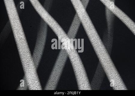 abstract design of shadows and light through curved shaped openings in balcony railing onto concrete floor textured wavy design horizontal background Stock Photo