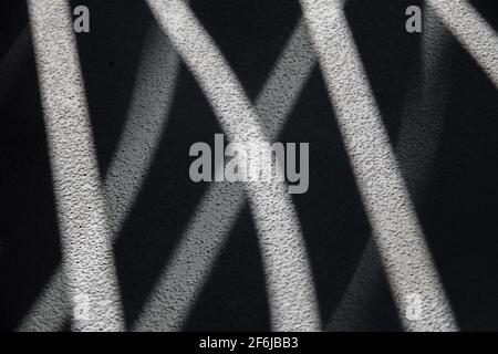 abstract design of shadows and light through curved shaped openings in balcony railing onto concrete floor textured wavy design horizontal background Stock Photo