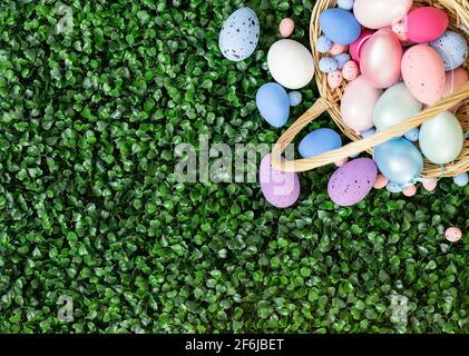 Easter colorful eggs in a basket on the green grass. Beautiful Easter composition. Copy space, top view, flat lay. Stock Photo