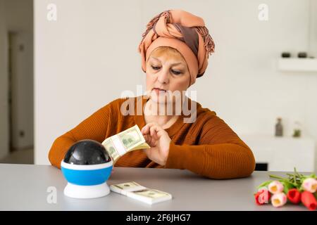 Female Fortuneteller or esoteric Oracle, sees in the future by looking into their crystal ball during a Seance to interpret them and to answer Stock Photo