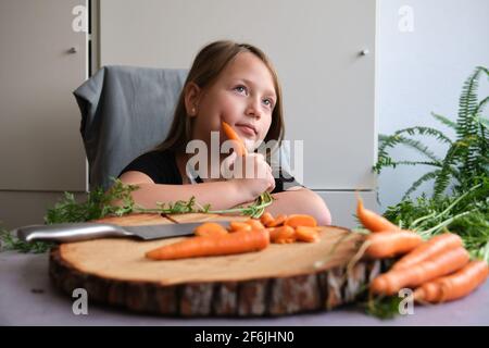 Little girl cuts fresh carrots in the kitchen Stock Photo