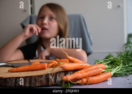 Little girl cuts fresh carrots in the kitchen Stock Photo