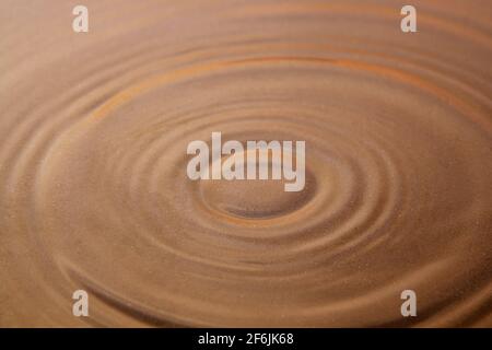 Circles on the surface of the water, through which the sand is visible. Background image. Close-up Stock Photo