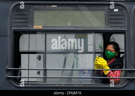 A lady wearing protective mask and gloves inside a public bus in Kolkata, India. Stock Photo