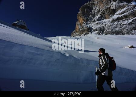 Dolomiten, schöne Frau beobachtet die schneebedeckten Berge und Felsen am winterlichen Langkofel oder Sasso Lungo in Südtirol in den Dolomiten Stock Photo