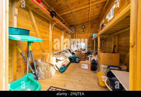 Interior of a half empty but messy wooden garden shed or tool shed in the UK. Stock Photo
