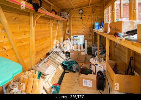 Interior of a half empty but messy wooden garden shed or tool shed in the UK. Stock Photo