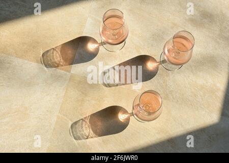 Three Glasses Of Rose Wine and Shadow on Stone Table Stock Photo