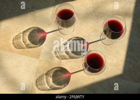 Three Glasses Of Red Wine and Shadow on Stone Table Stock Photo