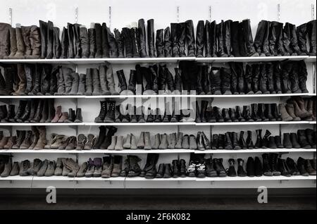 Rows of old used women's woments dress shoes and boots at thrift store on sale Stock Photo