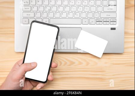 Online paying shopping, electronic payment with mockup credit card, mockup cell phone mockup, laptop. man hand holding mobile phone, using credit card Stock Photo