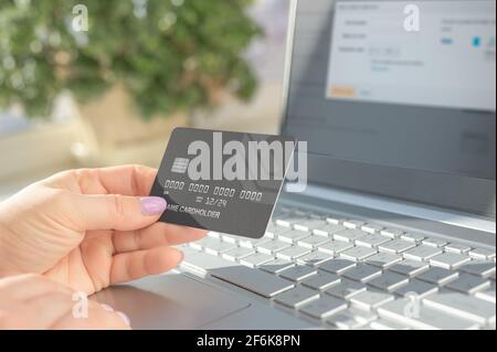 Hand holding credit card and using laptop. Online shopping, e-commerce, internet banking, spending money. woman using laptop and holding credit card m Stock Photo