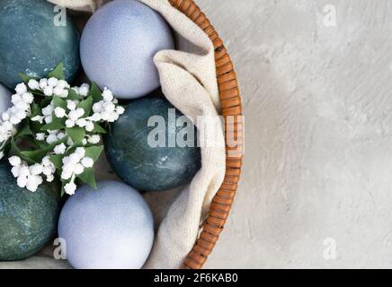 Easter eggs in a basket with artificial flowers are painted with natural dyes. Hibiscus tea and red cabbage Stock Photo