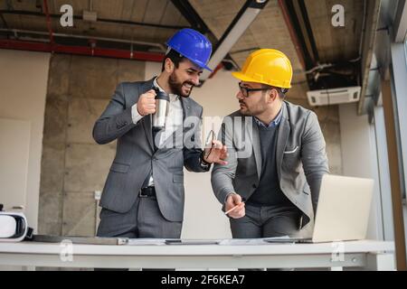 Two architects standing in building in construction process and talking about big project. Stock Photo