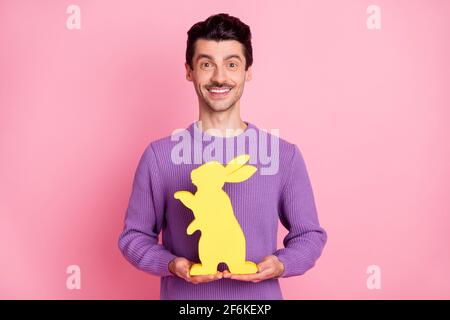 Photo of handsome cute young guy wear violet sweater holding yellow easter bunny isolated pink color background Stock Photo