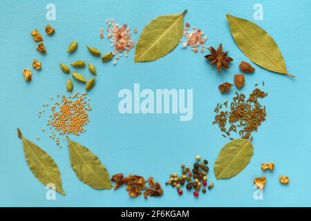 Various spices laid out on a blue background with round copy space, cumin, paprika, mustard, himalayan salt, badyan, bay leaf Stock Photo