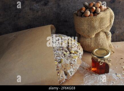 Homemade bread in paper on a wooden background. Nuts and honey. Source of vitamins. Stock Photo