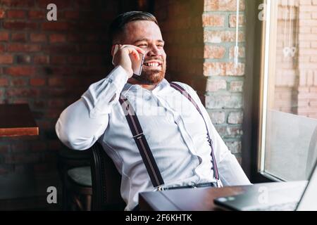Young businessman talking over a phone in a cafe, smiling Stock Photo