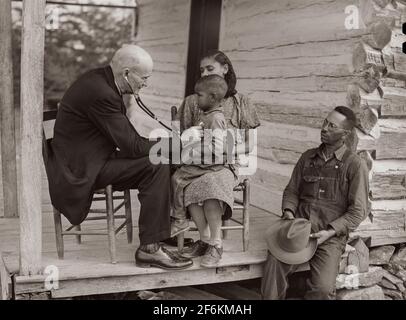Dr. S.A. Malloy examining Louis Graves and his family on their front porch. They are FSA (Farm Security Administration) borrowers. Caswell County, North Carolina. 1940. Stock Photo