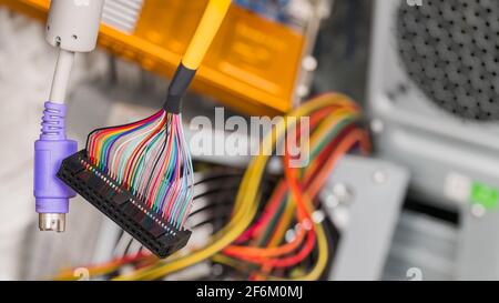 Colored hanging cables, connectors on e-waste heap background. Parallel multi wire or serial PS2 interface to computer storage device, keyboard, mouse. Stock Photo