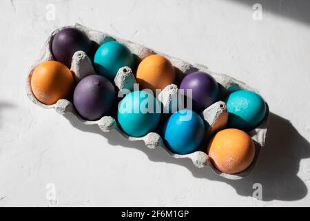 10 colorful Easter Eggs in blue, turquoise, purple, and orange in an egg carton. Stock Photo